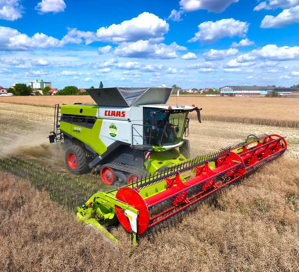 Kombajn CLAAS sklízí řepku, v pozadí traktor s návěsem.