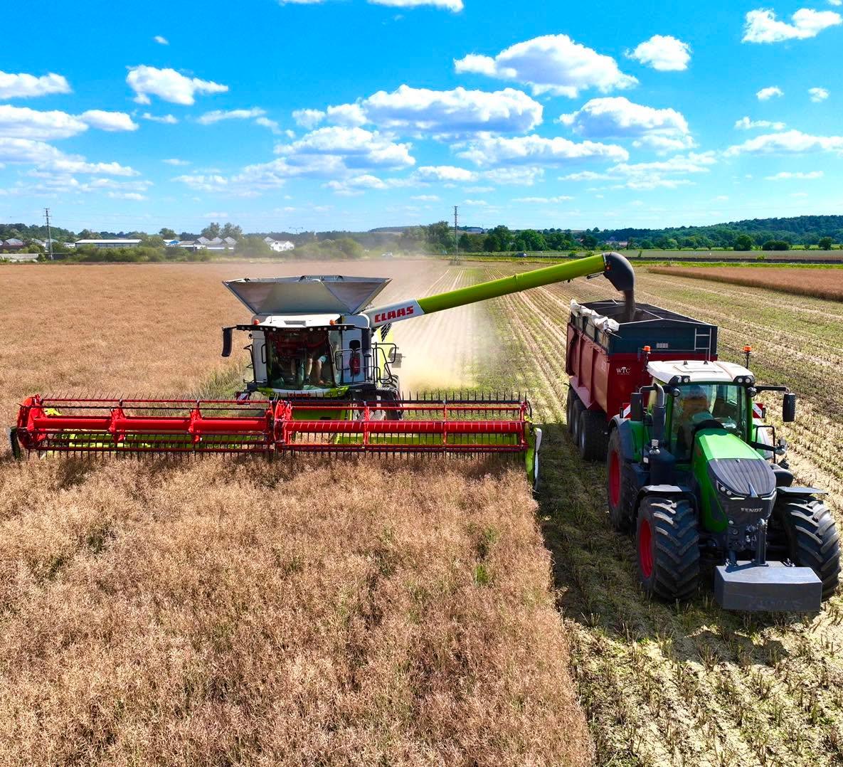 Kombajn CLAAS při sklizni řepky přesýpá zrno do návěsu taženého traktorem Fendt.
