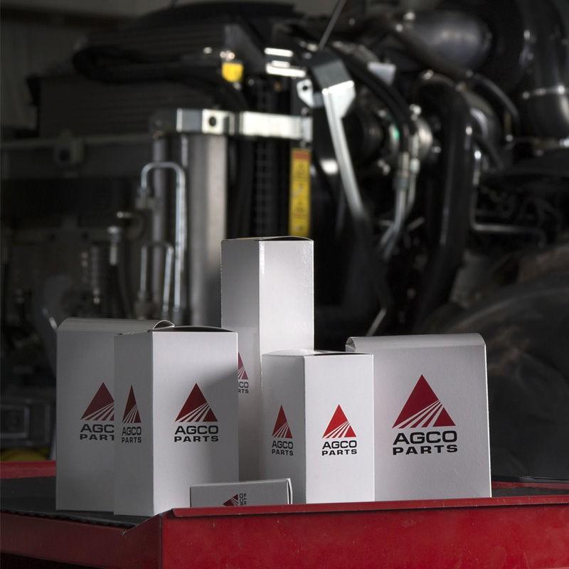 Krabice originálních náhradních dílů AGCO Parts před motorem traktoru.